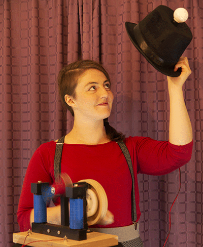 Natasha uses a hand cranked generator to power a blinking light on a top hat.